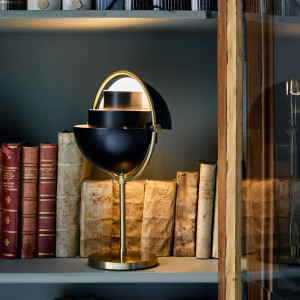 Imagen ambientada en estantería Multi Lite portable lamp latón con pantalla negra mate de Gubi